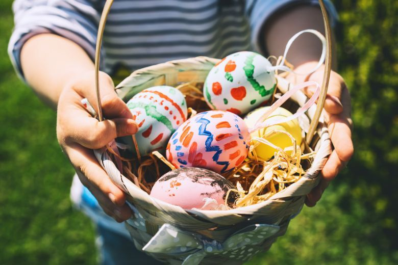 someone holding an easter basket full of colorful easter eggs