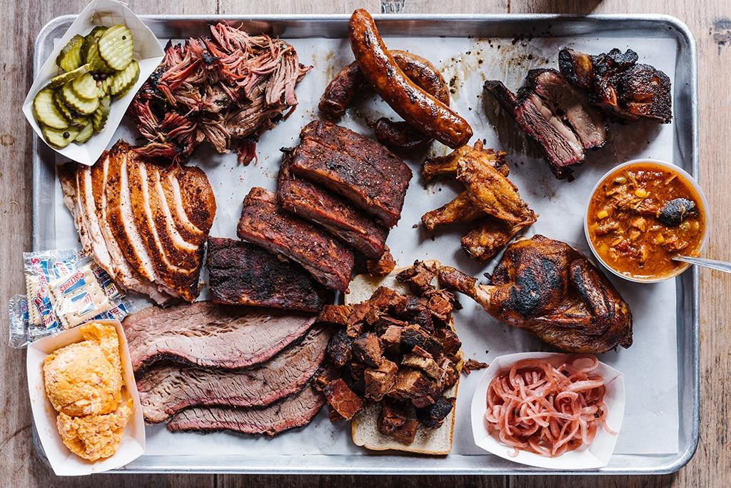 Barbecue platter with brisket, ribs, pulled pork, sausage, smoked chicken, pickles, and sides at a St. Simons Island restaurant.